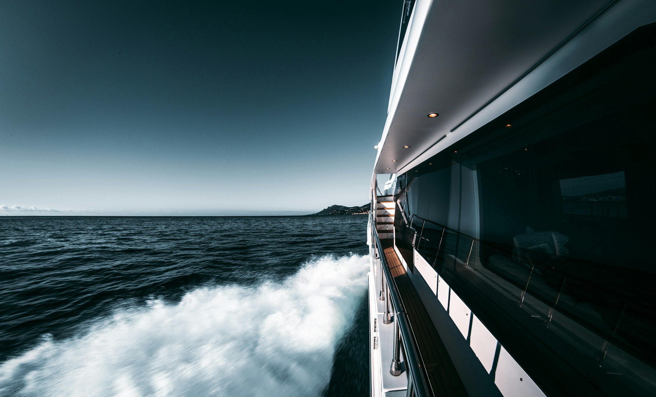 A motor yacht's wake streaming along its dark hull