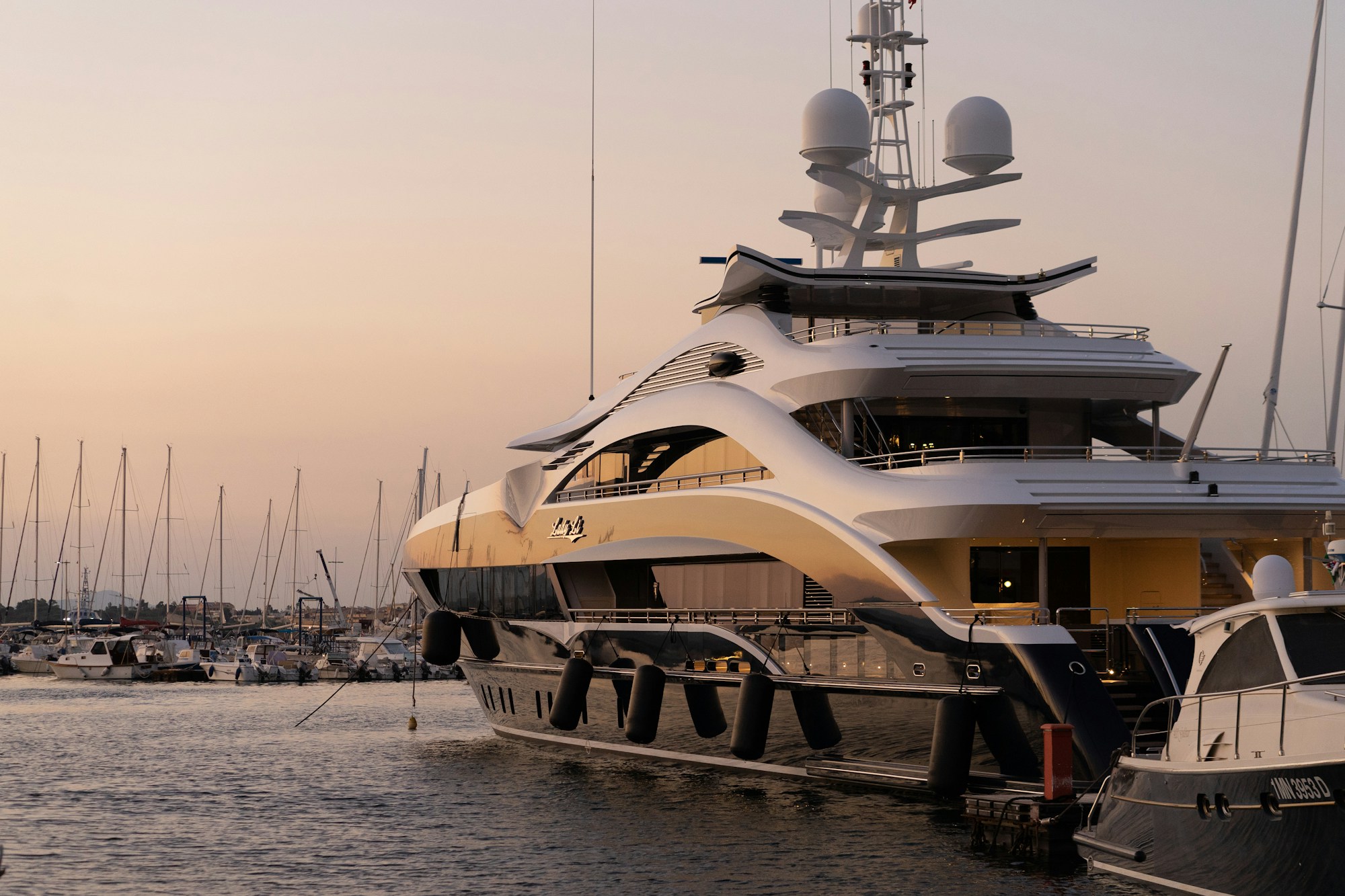A luxury yacht resting in a marina at golden hour